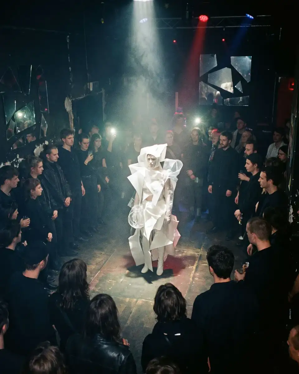 Artwork Spiegelsaal: Performerin in weißem Skulpturenkostüm, das Publikum steht im Kreis im Dunkeln